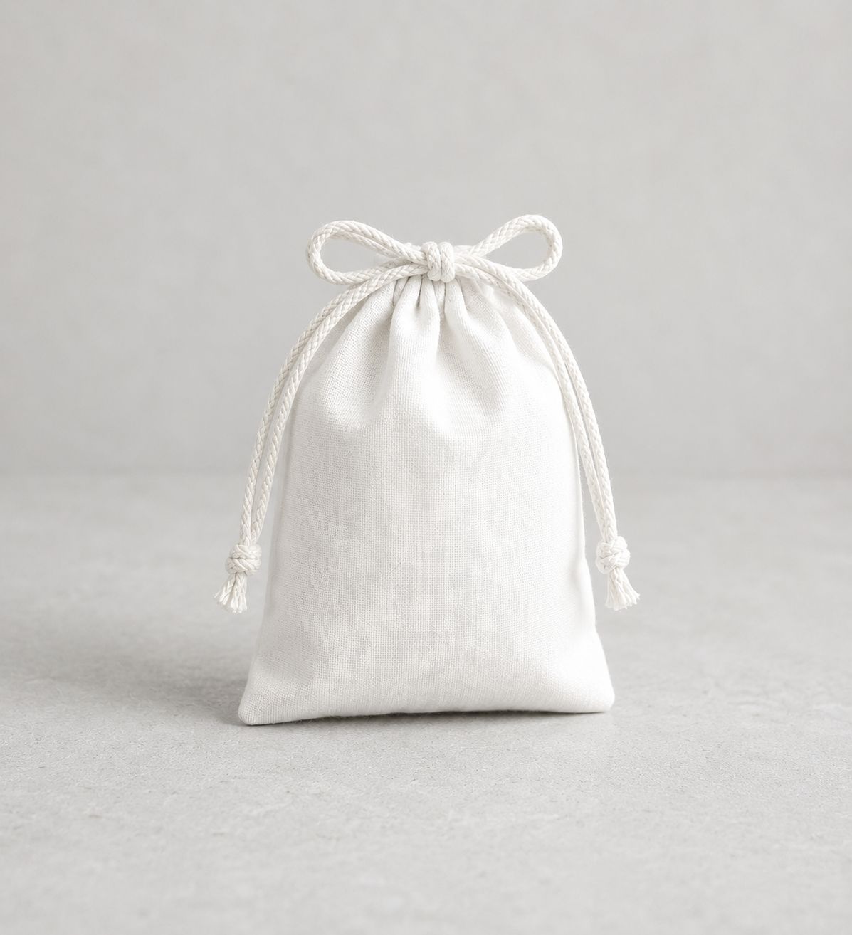 White cloth drawstring pouch on a plain grey surface