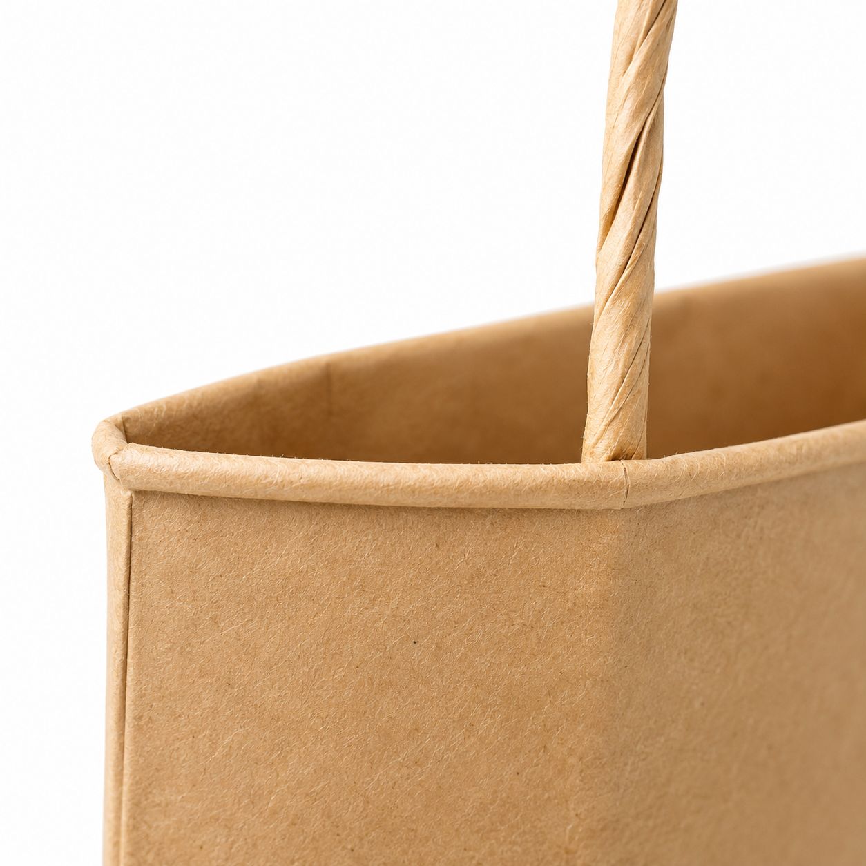 Close-up of the top edge of a kraft paper bag against a plain wall