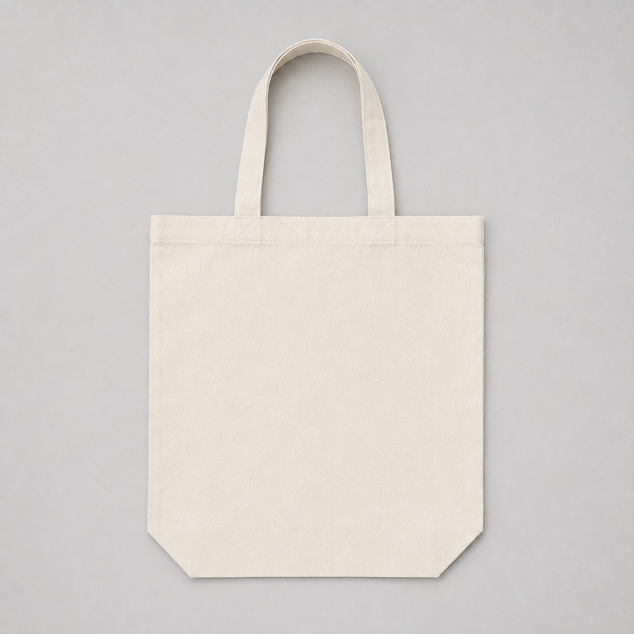Plain natural canvas tote bag laid flat on a light grey background